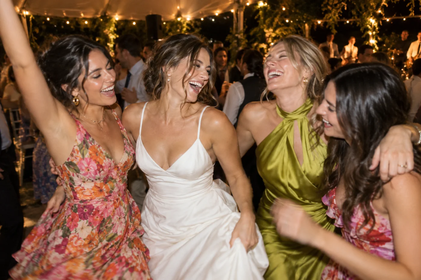 A phone camera view of a bride laughing and dancing with friends at a wedding